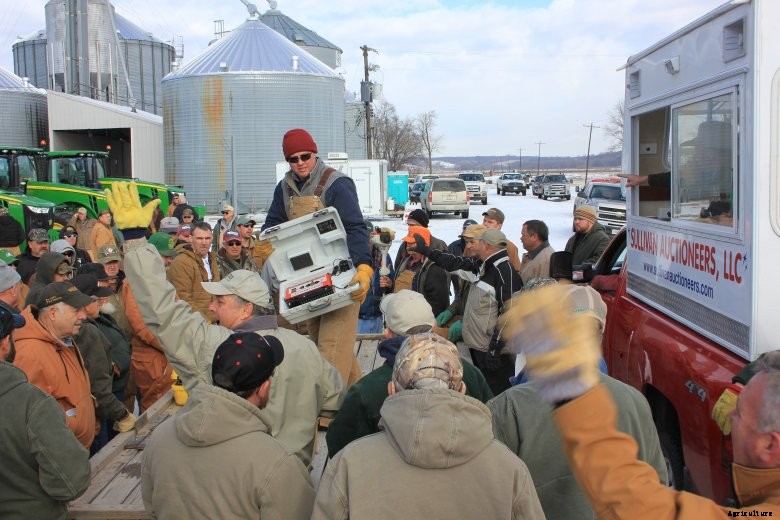 A crowd gathers around an auctioneer at a winter machinery auction